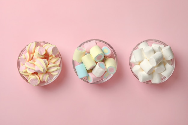 Bowls with marshmallows on pink background