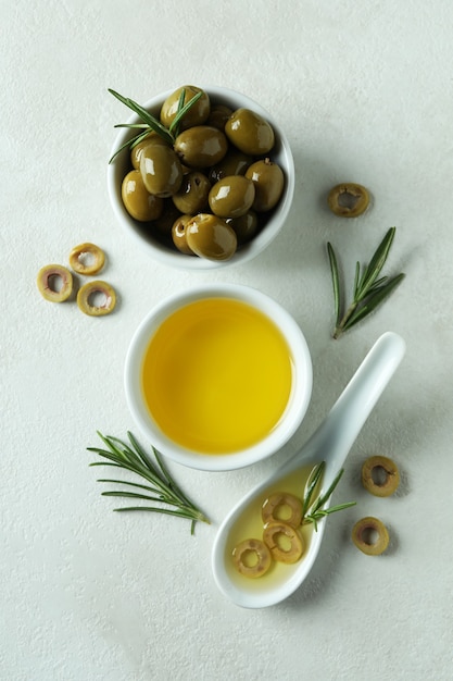 Bowls with olives and oil on white textured surface