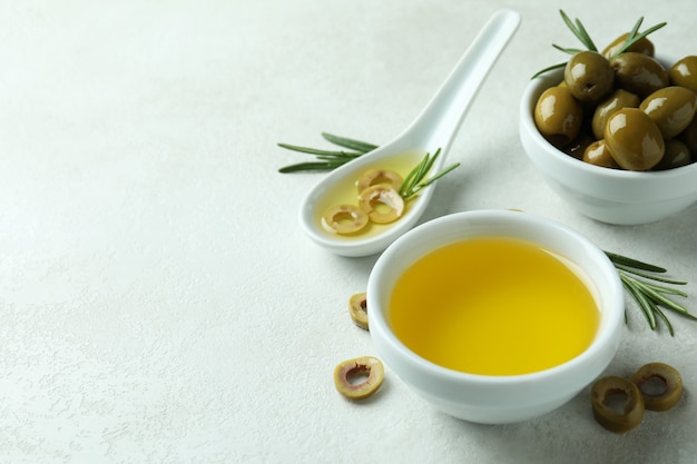 Bowls with olives and oil on white textured surface