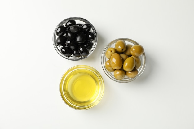 Bowls with olives and oil on white, top view