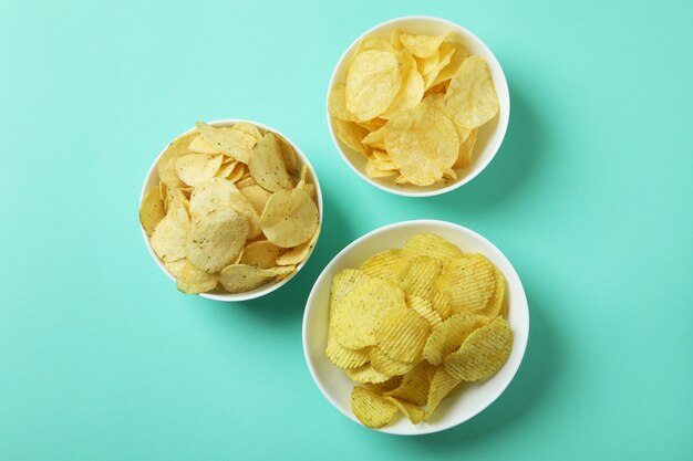 Bowls with potato chips on mint surface