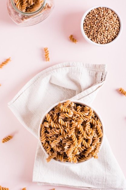 Bowls with raw buckwheat pasta and groats on the table Alternative to wheat Top and vertical view