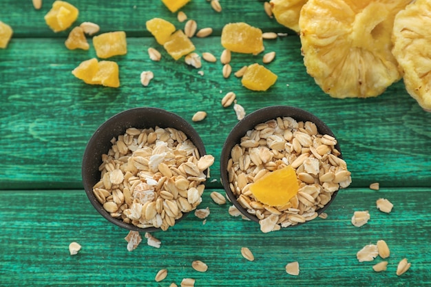 Bowls with raw oatmeal on wooden surface