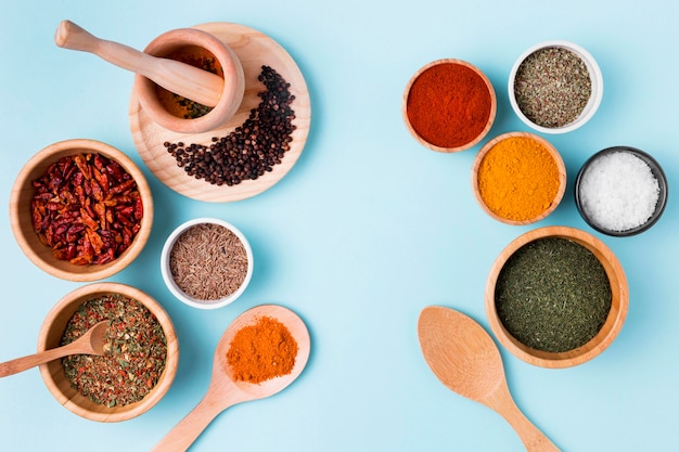 Bowls with spices on blue background