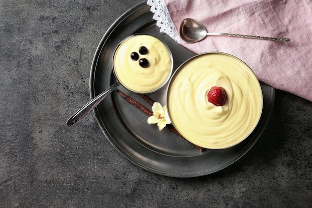 Bowls with tasty vanilla pudding on grey background top view