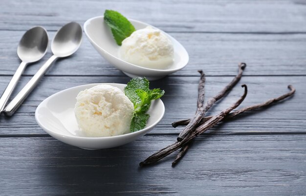 Bowls with yummy vanilla ice cream on wooden table