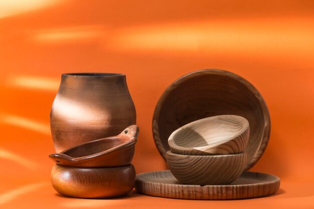 Bowls and a wooden plate with a vessel and a ceramic bowl located on an orange background