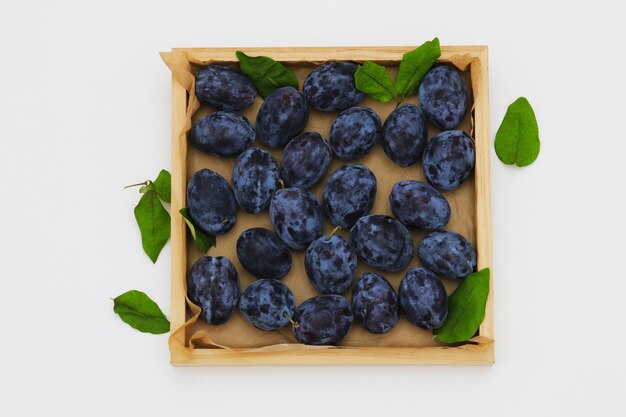 A box of blueberries with green leaves on a white background.
