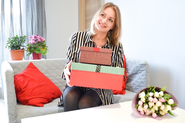 Box cadeau voor vrouwen. Het meisje opent een geschenkdoos. De vreugde van verrassing. Vrouw met bloemen.