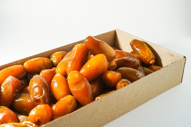 A box of date fruit sits on a white table.