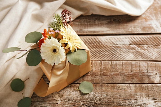 Коробка украшена цветами на деревянном фоне