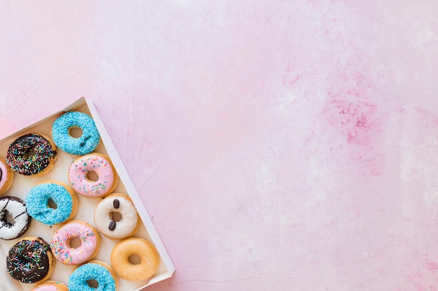 Scatola di ciambelle fresche su sfondo rosa