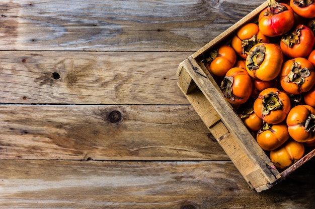 Box of fresh fruits persimmon kaki on wooden background