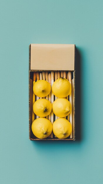 Photo a box of lemons on a blue surface