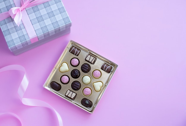 Коробка шоколадных конфет с розовым бантом на розовом фоне