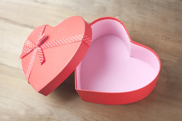 Photo box in the shape of heart on wooden background.