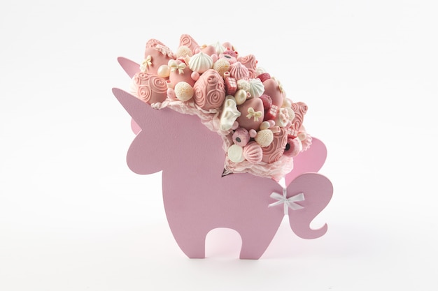 Box in the shape of a unicorn filled with pink sweets, strawberries in chocolate on white