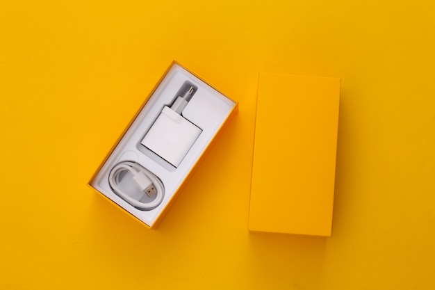 Box for a smartphone with a charger on yellow