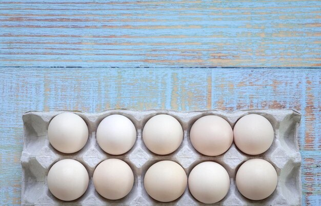 Box of white eggs on wood background