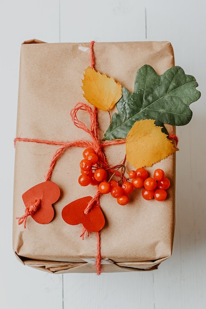 Box with autumn gift wrapped in kraft and tied rope with hearts ecofriendly biodegradable packaging ...