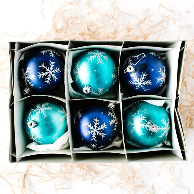 Box with bright blue christmas balls on white background.