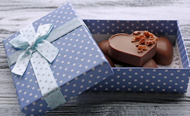 Box with chocolate hearts on wooden background