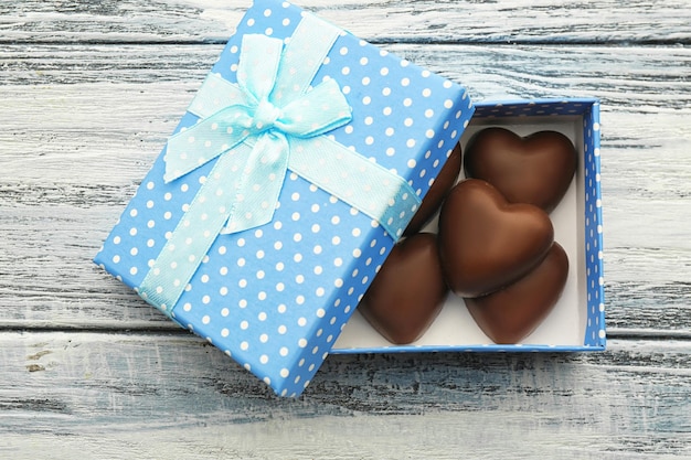 Box with chocolate hearts on wooden background