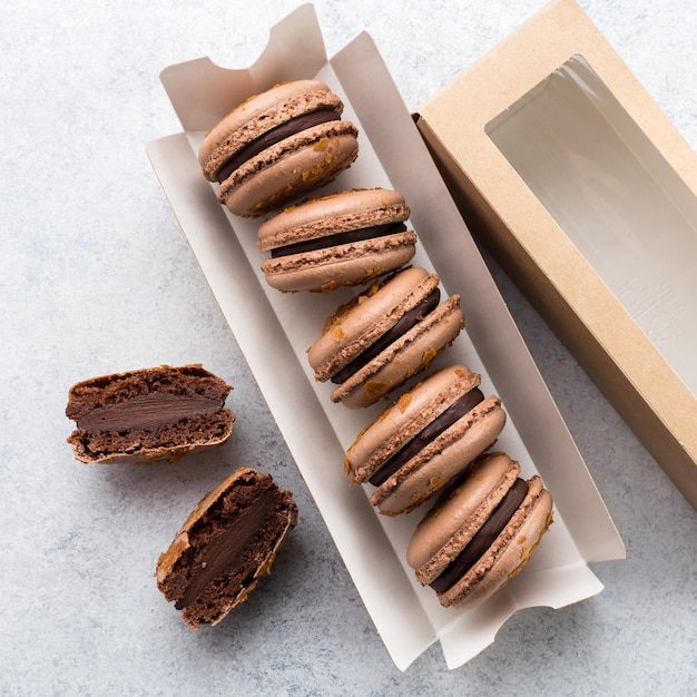 Box with chocolate tasty macarons on white background