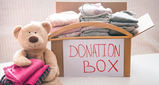 Box with clothes for charity and teddy bear with hanger