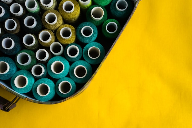 Box with coils with colored threads on a yellow table