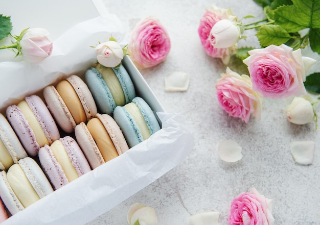 Box with delicious colorful macaroons and rose flowers