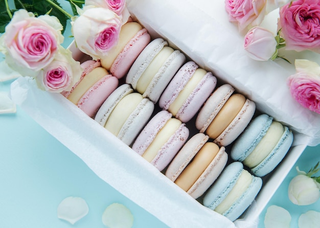 Box with delicious colorful macaroons and rose flowers