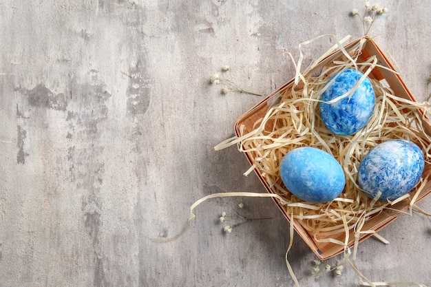 Box with Easter eggs on grey table