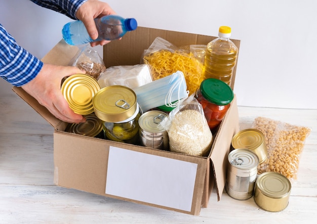 Box with food stock. cardboard box with butter, canned food,\
cereals and pasta. reserve. donation.