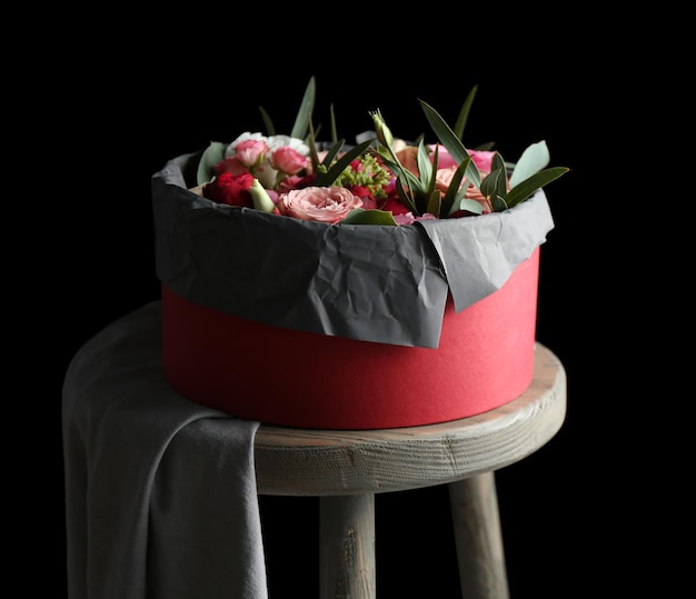 Box with fresh flowers and macaroons on the chair black background