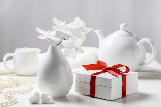 Коробка с подарком и белой орхидеей на белом фоне.