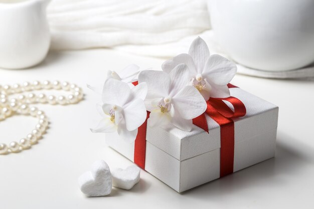 Box with a gift and a white orchid on a white background.