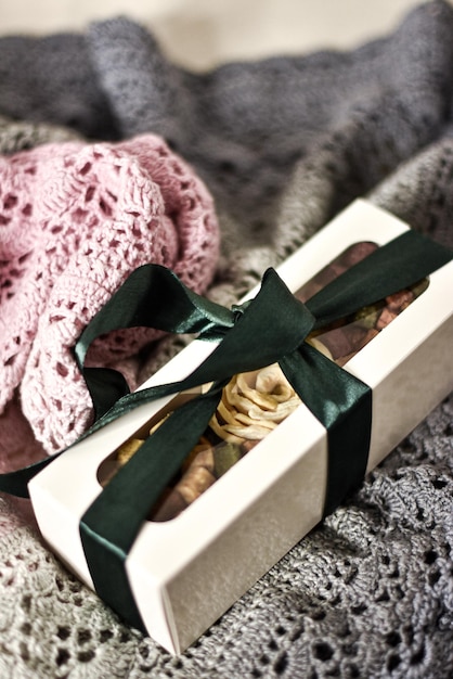 A box with a green ribbon tied around it and a pink knitted blanket.