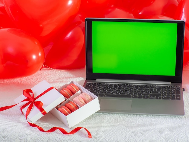 Photo box with macaron cookies and laptop with chroma key screen on the bed