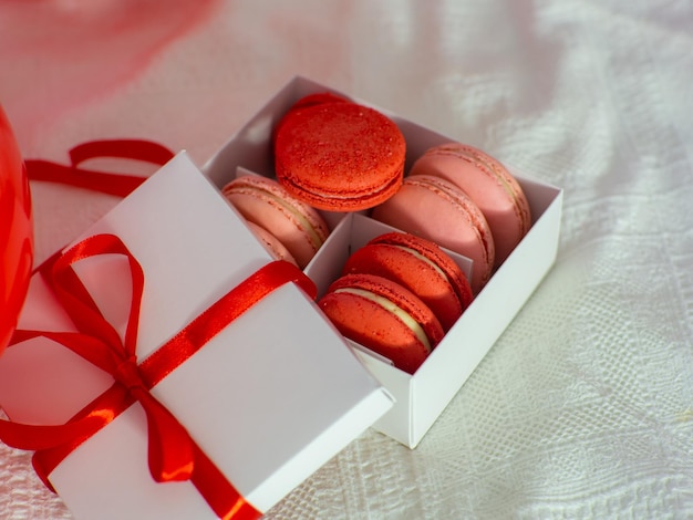 Box with macaron cookies and red baloons on the bed
