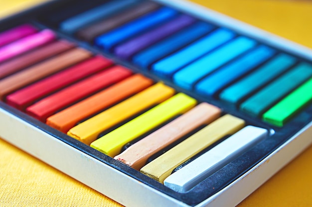 A box with new colorful pastel crayons. Small depth of field.