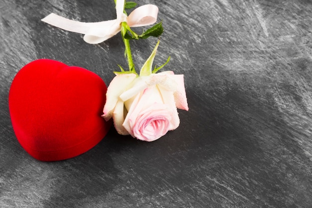 Box with a ring and pink rose on a dark background. Copy space