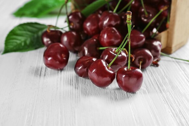 Box with scattered sweet cherries on table