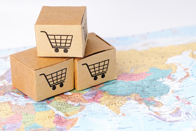 Фото Коробка с логотипом магазинной тележкаи на карте азии: импорт, экспорт, покупки в интернете или электронная коммерция, служба доставки, доставка товара, торговля, концепция поставщика.