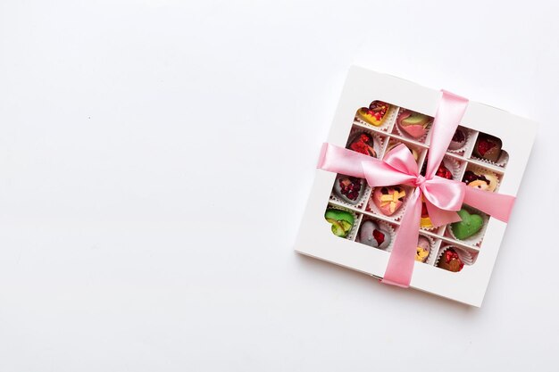 Photo box with sweet chocolate candies on color background various candy sweets valentines day gift box top view flat lay with copy space