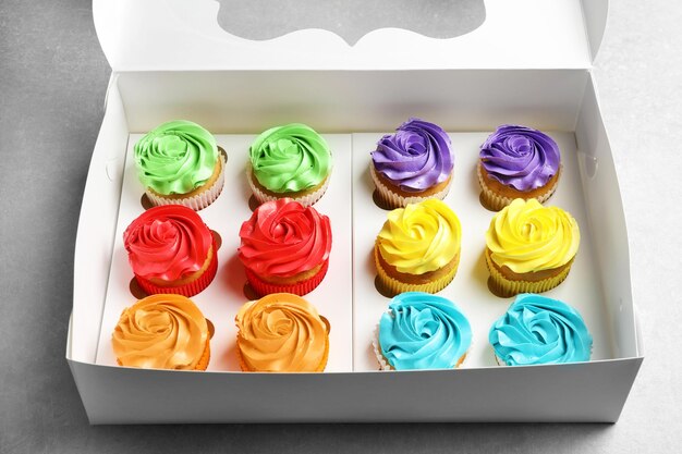 Box with tasty cupcakes on table