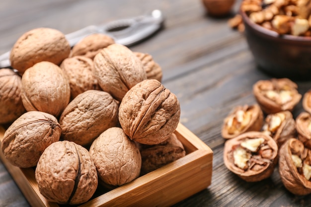 Box with tasty walnuts on wooden table