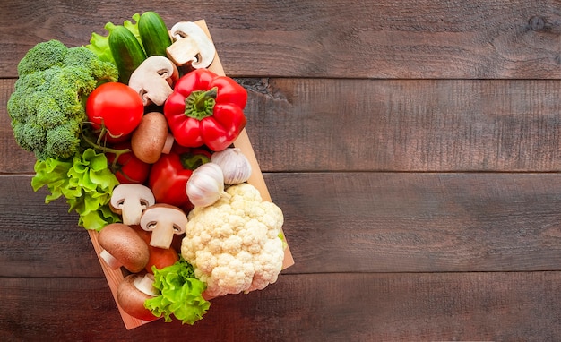 Box with vegetables on wooden background