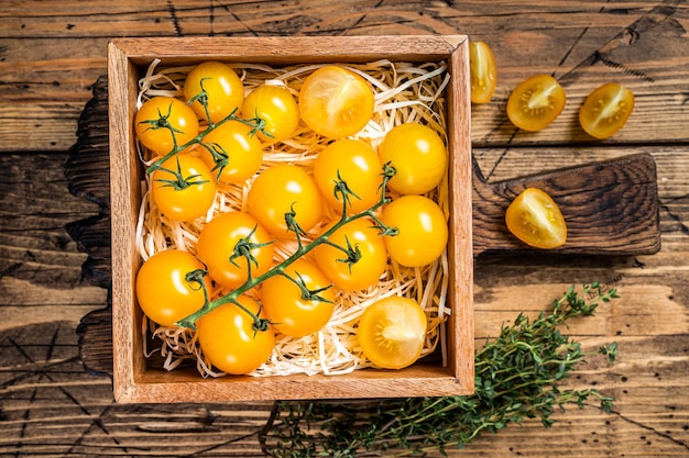 Box with yellow cherry tomato. wooden background. Top view.