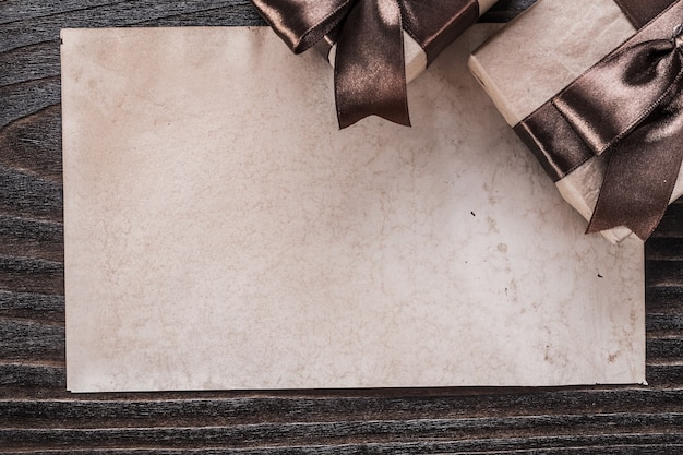 Boxed gifts with tied brown bows paper on wooden board.